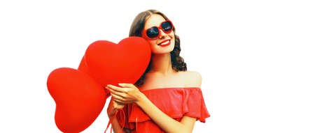 Portrait of happy smiling woman with red heart shaped balloon wearing sunglasses isolated on white backgroundの写真素材