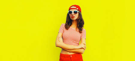 Summer portrait of young woman model wearing baseball cap, red shorts on yellow backgroundの写真素材