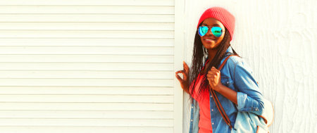 Portrait of happy smiling young african woman model wearing sunglasses, colorful clothes on white background, blank copy space for advertising textの写真素材