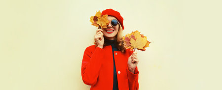 Autumn portrait of happy smiling young woman with yellow maple leaves wearing red french beret on...