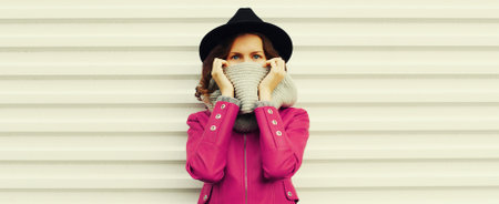 Portrait of unknown woman covering her face with scarf wearing black round hat on white backgroundの写真素材