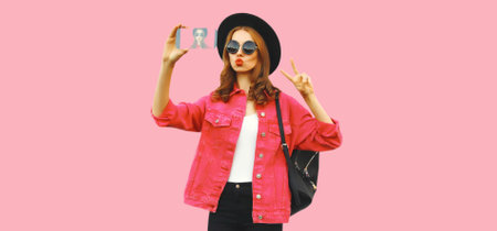 Portrait of modern stylish young woman taking selfie with smartphone blowing her lips sends kiss...