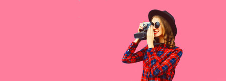 Portrait of happy smiling young woman photographer with film camera on pink background, blank copy space for advertising textの写真素材