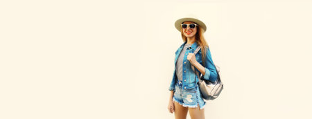 Portrait of smiling young woman wearing summer straw hat, backpack and shorts on white background,...