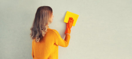 House cleaning concept - woman in rubber protective gloves holding dry microfiber rag wiping the...
