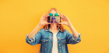 Close up of modern young woman stretching her hands taking selfie with smartphone on yellow...