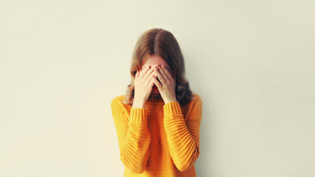 Upset sad crying woman covering her eyes with her hands while experiencing mental or physical sufferingの写真素材