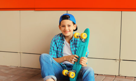 Happy smiling teenager boy with skateboard in casual wear on city streetの写真素材