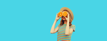 Summer, nutrition, diet and vegetarian concept. Happy healthy cheerful young woman covering her eyes with slices of orange fruits and looking for something on blue backgroundの写真素材