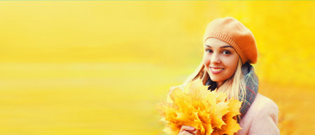 Portrait of beautiful happy smiling caucasian blonde woman with yellow maple leaves wearing french...