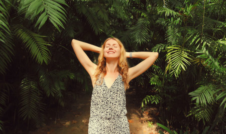 Happy smiling young woman enjoying nature in forest on tropical tree backgroundの写真素材