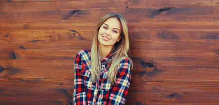 Portrait of beautiful caucasian blonde smiling young woman in casual checkered shirt in the cityの写真素材