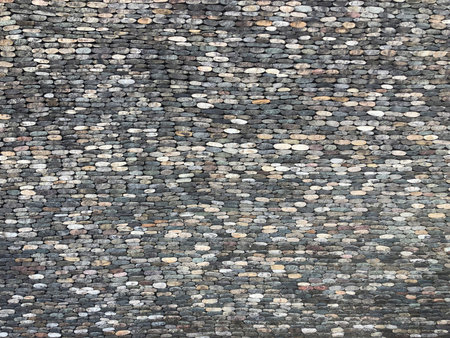 Paved pavement road or wall with gray small round smooth granite stones, cobblestones top view, background photo textureの写真素材