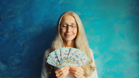 Portrait of happy smiling middle aged woman holding cash money in dollar bills in her hands
