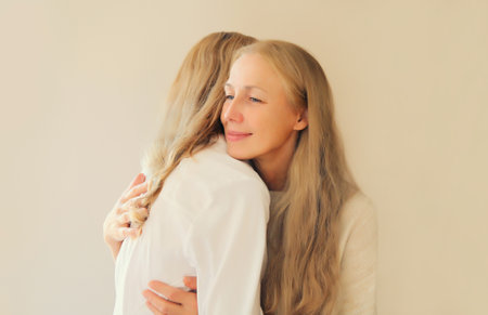 Portrait of happy smiling caucasian middle aged mother or sister and adult daughter together on studio backgroundの写真素材