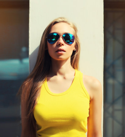 Portrait of modern caucasian young blonde woman posing in sunglasses on city streetの写真素材