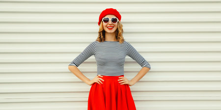 Portrait of beautiful happy smiling young woman model posing in red skirt, french beret, heart shaped sunglasses on white backgroundの写真素材