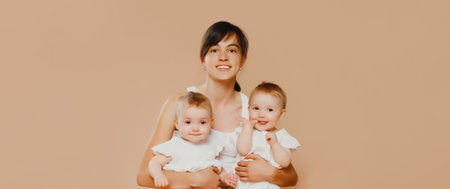 Happy cheerful smiling young mother holding baby on brown studio background