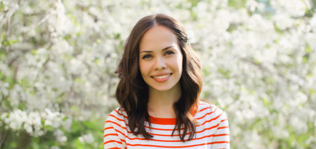 Portrait of lovely happy smiling young woman in spring blooming garden with white flowers on the...