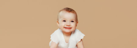 Portrait of happy cute baby crawling on the floor on brown studio backgroundの写真素材