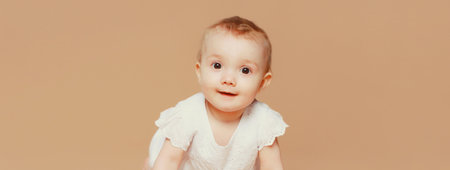 Portrait of happy cute baby crawling on the floor on brown studio backgroundの写真素材