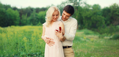 Wedding concept, happy lovely young couple, man proposing a ring to his beloved woman outdoors in...