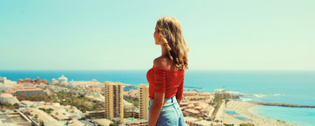Summer vacation, beautiful young woman tourist on top of the mountain looking around the city in Tenerife, Canary Islands, Spain. Aerial top view.の写真素材