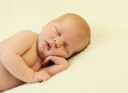 Close up portrait of sweet baby, infant sleeping lying on white bed at homeの写真素材
