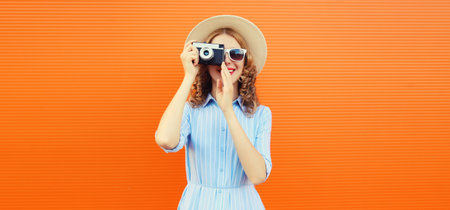 Portrait of happy young woman photographer with film camera, modern girl taking a picture in summer...
