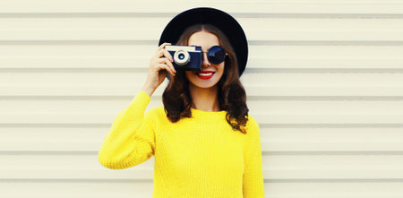 Portrait of happy smiling young woman photographer with film camera on white background