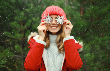 Winter day, happy smiling young woman with snowflakes toys having fun enjoys snow, warm weather...