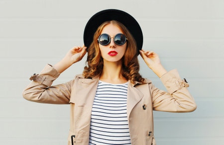 Fashion portrait pretty woman wearing a black hat sunglasses over grey backgroundの写真素材