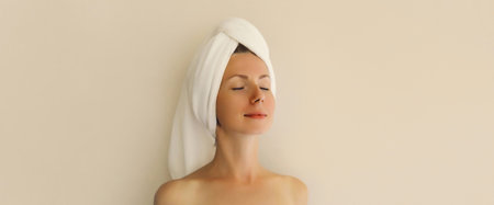 Natural beauty portrait of happy young caucasian woman enjoying her clean skin drying wet hair with white bath towel on her headの写真素材