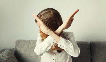 Close-up upset young woman shows stop, no or enough sign with palm of hand, refusal gesture,...