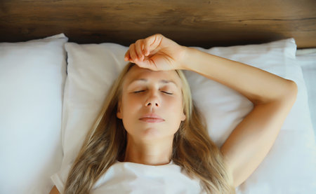 Exhausted tired woman touching head, suffering from headache, stress, fatigue, temples pain, migraine, loud noise, tension lying on the pillow in bed in bedroom at homeの写真素材