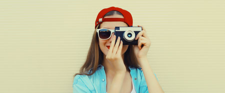 Portrait of happy young woman photographer with film camera, modern girl taking a picture standing on white backgroundの写真素材