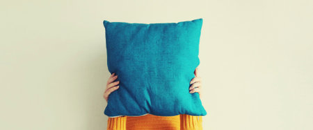 Healthy sleep, woman covering her head with colorful soft pillow holding in hands at home in morningの写真素材