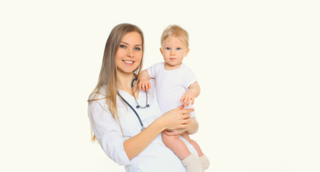 Portrait of happy smiling young woman doctor pediatrician holding little baby standing on white backgroundの写真素材