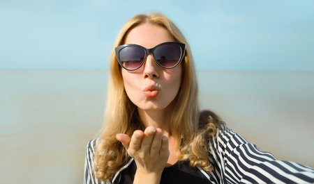 Summer portrait of happy cheerful young woman taking selfie with smartphone on the beach, girl...