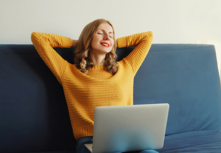 Happy modern young woman relaxes while working with laptop, freelancer girl enjoying free time,...
