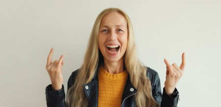 Portrait of happy stylish emotional mature woman overjoyed with crazy expression doing rock symbol...