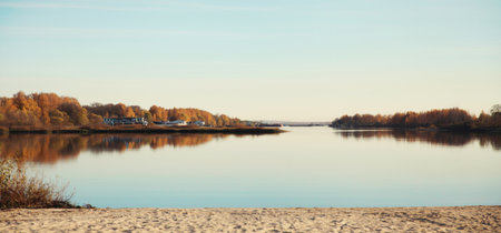 Nature background, beautiful autumn view of river landscape on the beach with reflection on water at sunny sunset in the eveningの写真素材
