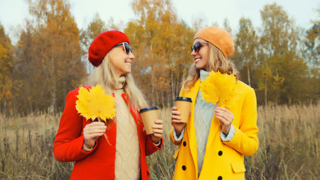 Happy young two women friends with autumn yellow leaves in park, stylish smiling girlfriends in...