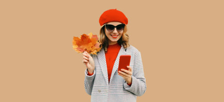 Autumn portrait of stylish happy smiling young woman with phone, beautiful girl holding yellow maple...
