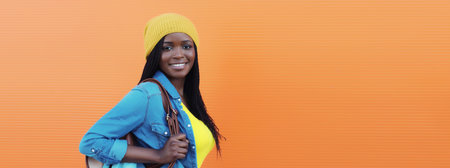 Portrait of happy stylish young African woman student in casual clothing with bag, black girl smiles...