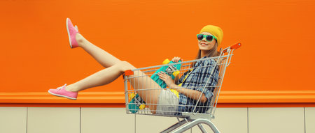 Stylish happy cheerful young woman with skateboard, modern teenage girl smiling having fun sitting...