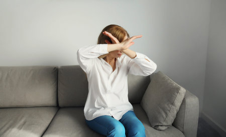 Upset young woman shows stop, no or enough sign with palm of hand, refusal gesture, domestic...