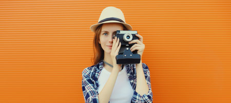 Portrait of young woman photographer with film camera, modern girl tourist taking a picture standing...