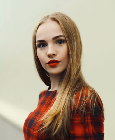 Close-up portrait of young blonde woman in red dress, girl posing looking at cameraの写真素材