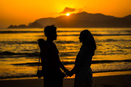silhouette image of two lovers who give promise sacred red beach in banyuwangiのeditorial素材
